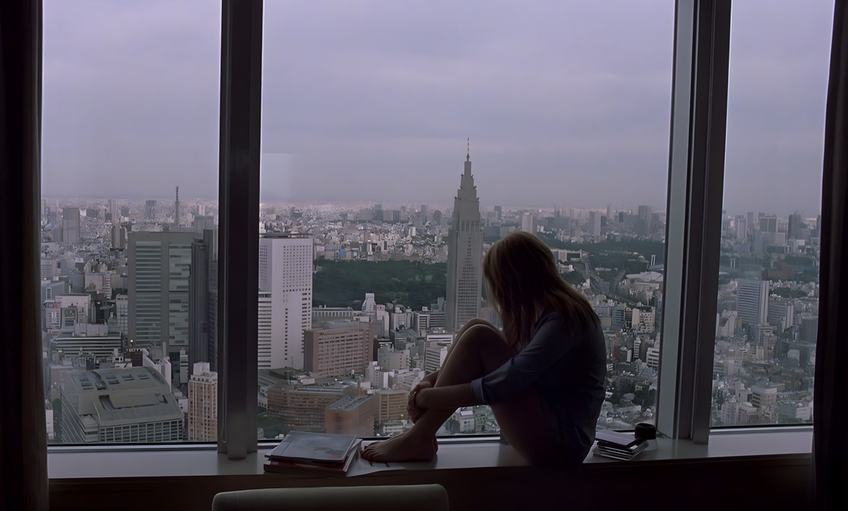 Charlotte assise sur le rebord de la fenêtre de sa chambre d’hôtel, face à Tokyo, dans Lost in Translation
